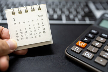 Hand holding January 2026 calendar with calculator for financial stress and budget crisis concept. financial anxiety, calculating monthly expenses, debt management.