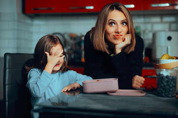 Mom Checking the Lunchbox After her Kid Gets Back from School. Mother and daughter having a snack from her packed meal 
