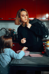 Tired Mom Gets Her Child Ready for School. Desperate mom rushes her kid who is still dressed in pajamas to go to school