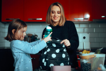 School Girl Putting Water Bottle in a Schoolbag Together with Mom. Daughter and her helpful mom getting ready for school together