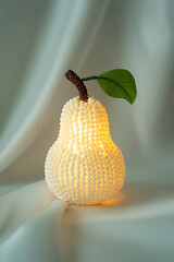 A decorative pearshaped lamp emitting a soft warm glow, placed on a draped white fabric surface