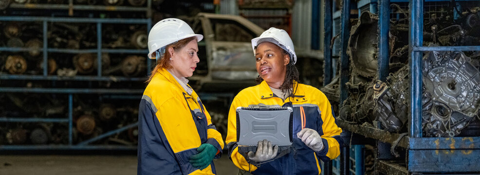 Banner Two female engineers in safety gear inspecting car parts inventory. workers technical walking old dirty car industry checking used auto parts by tablet industrial automotive warehouse Recycling - Powered by Adobe