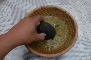 Traditional preparation of Mexican potatoes with chorizo and fresh green salsa using a volcanic stone mortar (molcajete)