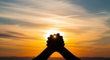 Hands clasped in hopeful prayer against a vibrant sunset sky symbolizing faith and spiritual connection