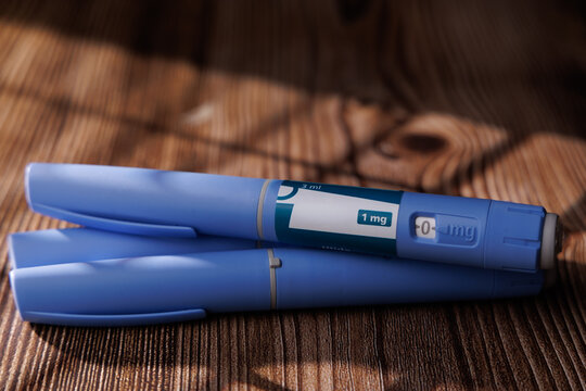 Semaglutide injector pens on a dark wood table at a 45 degree angle view for diabetes care and weight management pharmaceutical stock