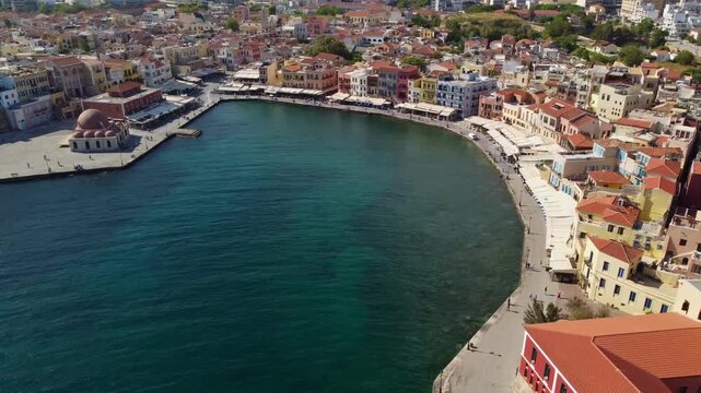 Circling to reveal Chania's picturesque Venetian Harbour; a popular tourist hotspot for wandering, dining and drinking on the Aegan Sea - Crete, Greece
