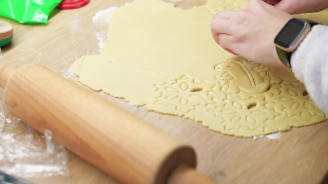 Close-up shot of festive cookie dough being shaped on a wooden surface. Perfect lighting highlights intricate patterns. Ideal for holiday baking themes in stock footage.
