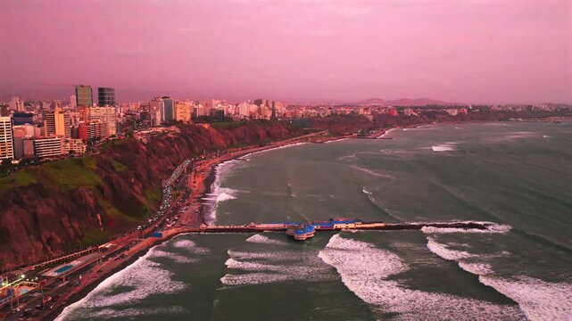 Miraflores Lima Peru Makaha Barranco beach coastal sunset aerial drone harbor view pink purple clear skies Pacific Ocean surfing cityscape skyscraper buildings ocean waves cars traffic circle right