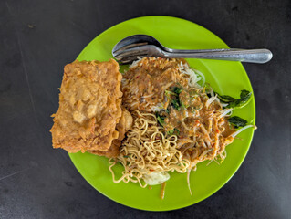 Pecel Vegetable Rice with Noodles and Fried Tempeh on a Green Plate
