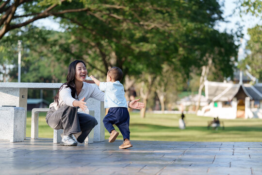 Asian mother embracing toddler son in outdoor park