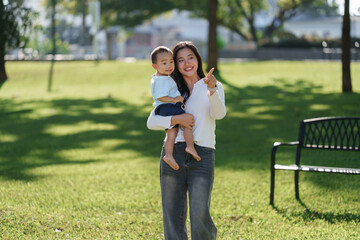 Mother holding child pointing outdoors in park