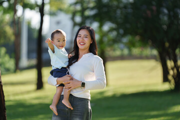 Happy asian mother holding baby son in park