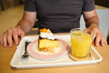 Man sitting at a cafe table enjoying a slice of pumpkin cheesecake with a beverage
