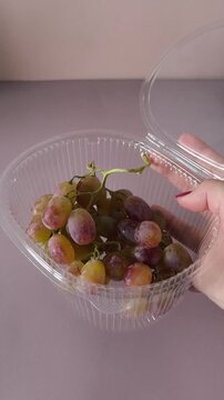 Open container of Taifi grapes in a woman's hand close-up. Storing berries