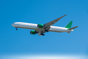 Obraz premium Passenger aircraft with landing gear down, flying in a bright blue sky. on the engines and tail, perfect for travel and transportation concepts.