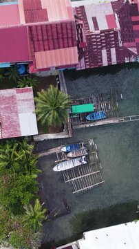 Vertical aerial topdown view showcasing stilt houses along turquoise waters on Bastimentos Island, Panama.