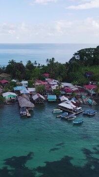 Vertical aerial view of Bastimentos Island in Panama, featuring a Caribbean village with houses and moored fishing boats.