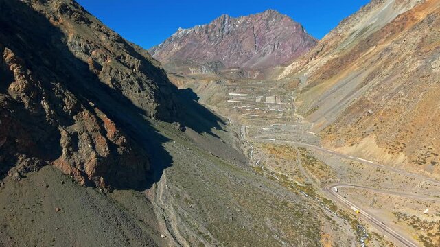 Aerial view establishing panoramic view of Cuesta Caracoles on a sunny day, dangerous curves at the entrance to Chile with mountainous surroundings. Slow motion