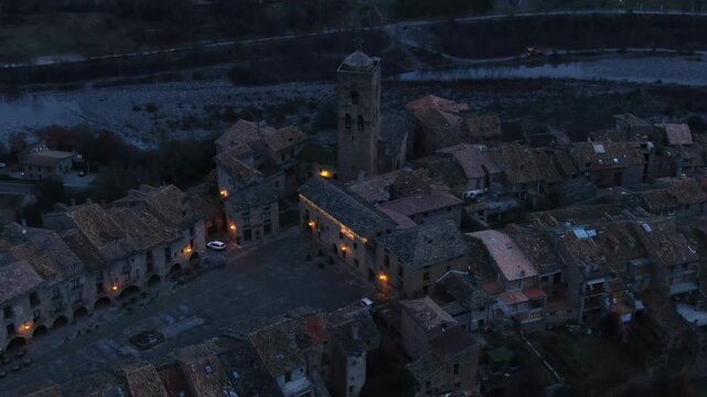 Majestic aerial view showing the illuminated historic old town of Ainsa in Spain during blue hour