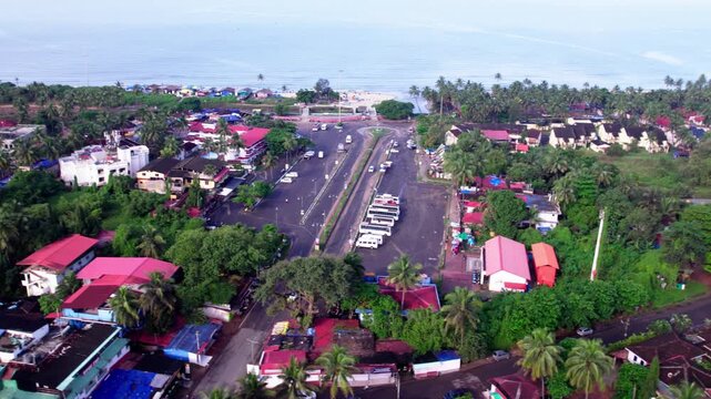 Parked vehicles with road, trees, hotels and beach at colva, goa, india. day time, stable shot, drone shot, 4k.