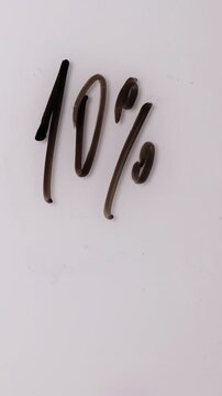 A hand writes percentages on a white board to show sales offers. The percentages are then erased and new percentages are written to reflect new deals.