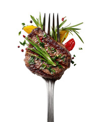 Grilled steak with herbs and vegetables speared on a fork