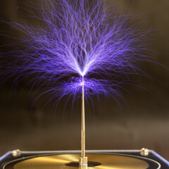Streams of violet plasma discharge from the top of a Tesla coil in a high-voltage experiment