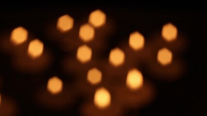 Multiple blurred candle lights create shifting warm bokeh as the soft glowing points subtly change positions across frames, forming a calming abstract atmosphere without defined emotion.