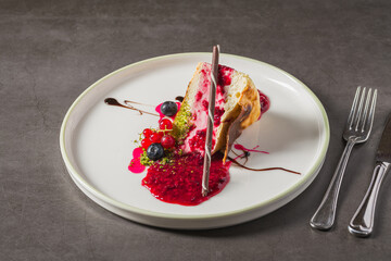 Cheesecake slice topped with fresh berries and vibrant sauce