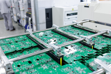 Stacks of green circuit boards in rack at modern electronics factory line