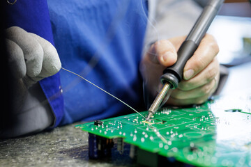Technician hand soldering printed circuit board for electronics repair and rework