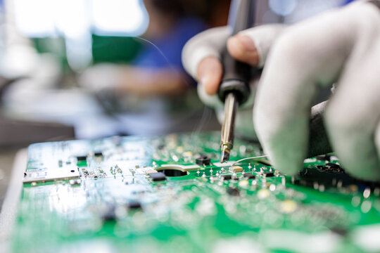 Closeup worker soldering electronic circuit board in electronics factory