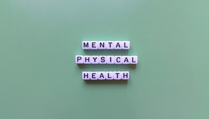 A close-up shot of three wooden blocks with purple lettering spelling out 'MENTAL PHYSICAL HEALTH' on a muted green background with a shallow depth of field, conveying a calm and thoughtful