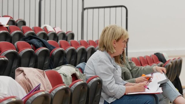 Mature students studying and reviewing paperwork while seated in a lecture hall during an adult education session, highlighting lifelong learning, continuing education, and personal development