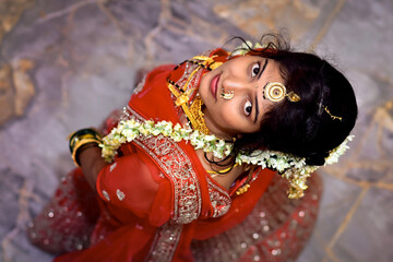 Top view of Indian wedding bride and groom looking up, dressed in traditional attire, captured from overhead angle during marriage ceremony.