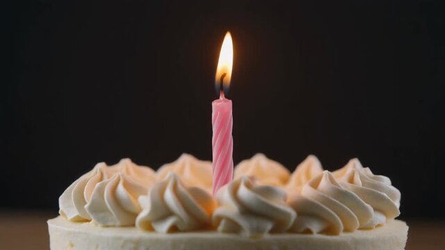 Close-up of a single lit birthday candle on a frosted cake, perfect for celebrations and special occasions