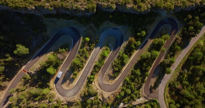 Top-down aerial of tourist camper van maneuvering through steep switchbacks of the A-1604 while descending from Mirador de Fuebla toward A&iacute;nsa, Spain.