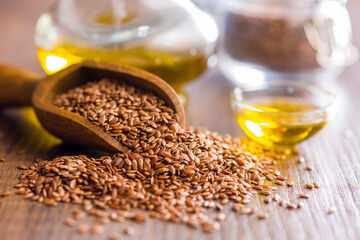 Brown linseed or flaxseed and oil. Healthy flax seed on wooden scoop on wooden table.