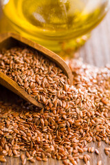 Brown linseed or flaxseed and oil. Healthy flax seed on wooden scoop on wooden table.