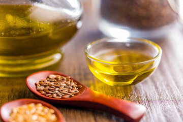 Brown linseed or flaxseed and oil. Healthy flax seed on wooden spoon on wooden table.