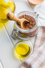 Brown linseed or flaxseed and oil. Healthy flax seed in jar on white table.