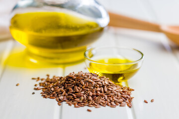 Brown linseed or flaxseed and oil. Healthy flax seed on white table.