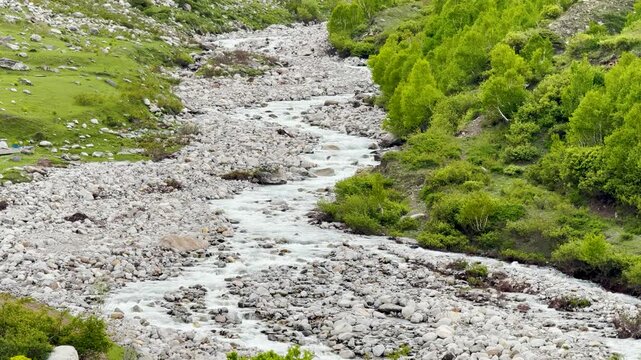 4K Landscape shot of a river stream flowing in the mountain valley as seen from Sural Bhatori in Pangi Valley of Chamba district, Himachal Pradesh, India. Scenic natural background with copy space.