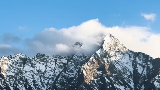 4K Landscape shot of clouds above the snowy Himalayan mountain peak during the winter season as seen from Killar in Chamba district, Himachal Pradesh, India. Scenic view of snowy mountains in winter.