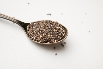 Chia seeds in old metal spoon on light gray background flat lay top view. Food background, healthy eating concept. Healthy dry organic chia seeds rich in omega-3, protein, vitamins and minerals