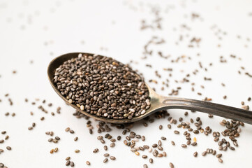 Chia seeds in old metal spoon on light gray background flat lay top view. Food background, healthy eating concept. Healthy dry organic chia seeds rich in omega-3, protein, vitamins and minerals
