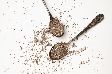 Chia seeds in old metal spoon on light gray background flat lay top view. Food background, healthy eating concept. Healthy dry organic chia seeds rich in omega-3, protein, vitamins and minerals