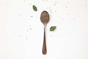 Chia seeds in old metal spoon on light gray background flat lay top view. Food background, healthy eating concept. Healthy dry organic chia seeds rich in omega-3, protein, vitamins and minerals