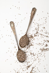 Chia seeds in old metal spoon on light gray background flat lay top view. Food background, healthy eating concept. Healthy dry organic chia seeds rich in omega-3, protein, vitamins and minerals