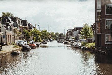 The beautiful canals of Leiden city centre surrounded by buildings, Dutch houses and boats along the water outdoor at daytime during summer in Leiden in The Netherlands with space for text.